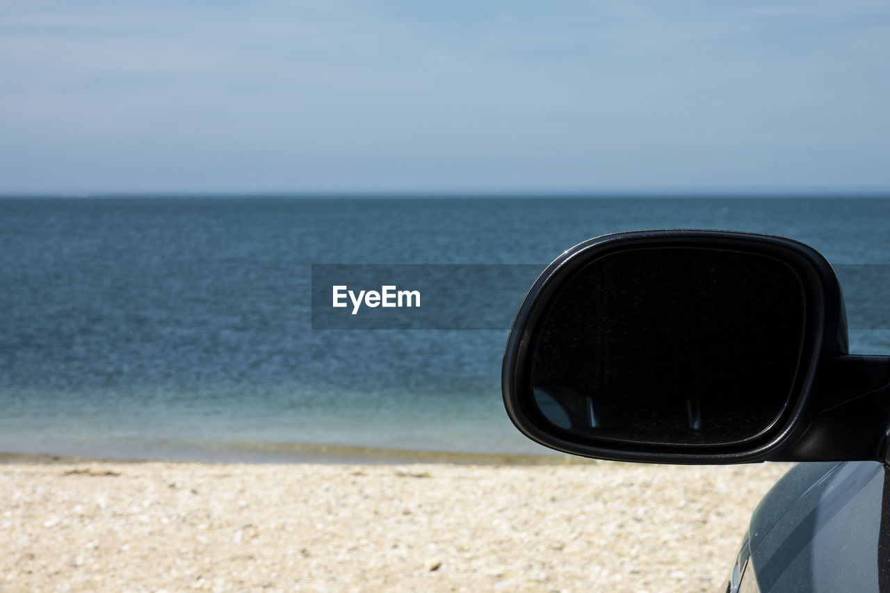 Close-up of sunglasses on beach against sky