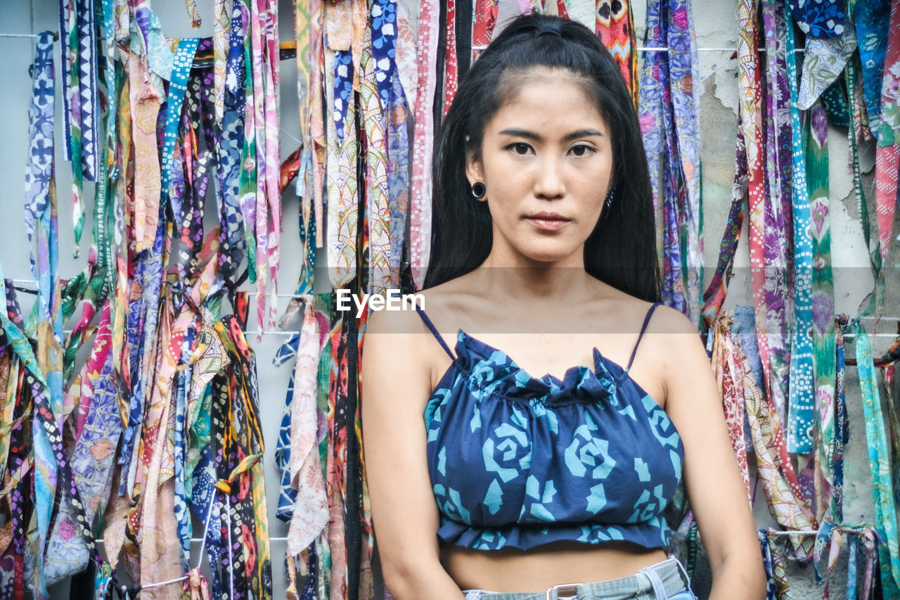 Portrait of beautiful young woman standing against multi colored background