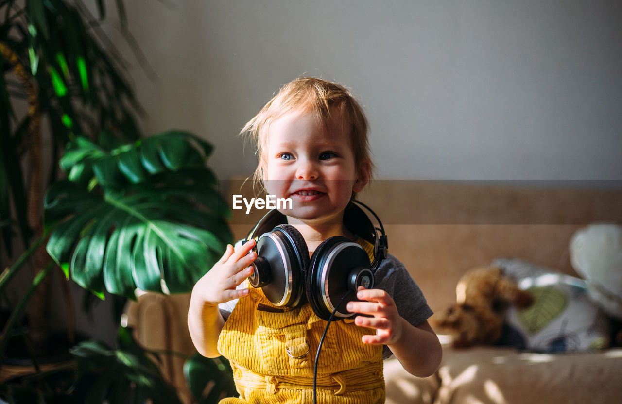 Funny little child having fun with headphones at home, portrait.