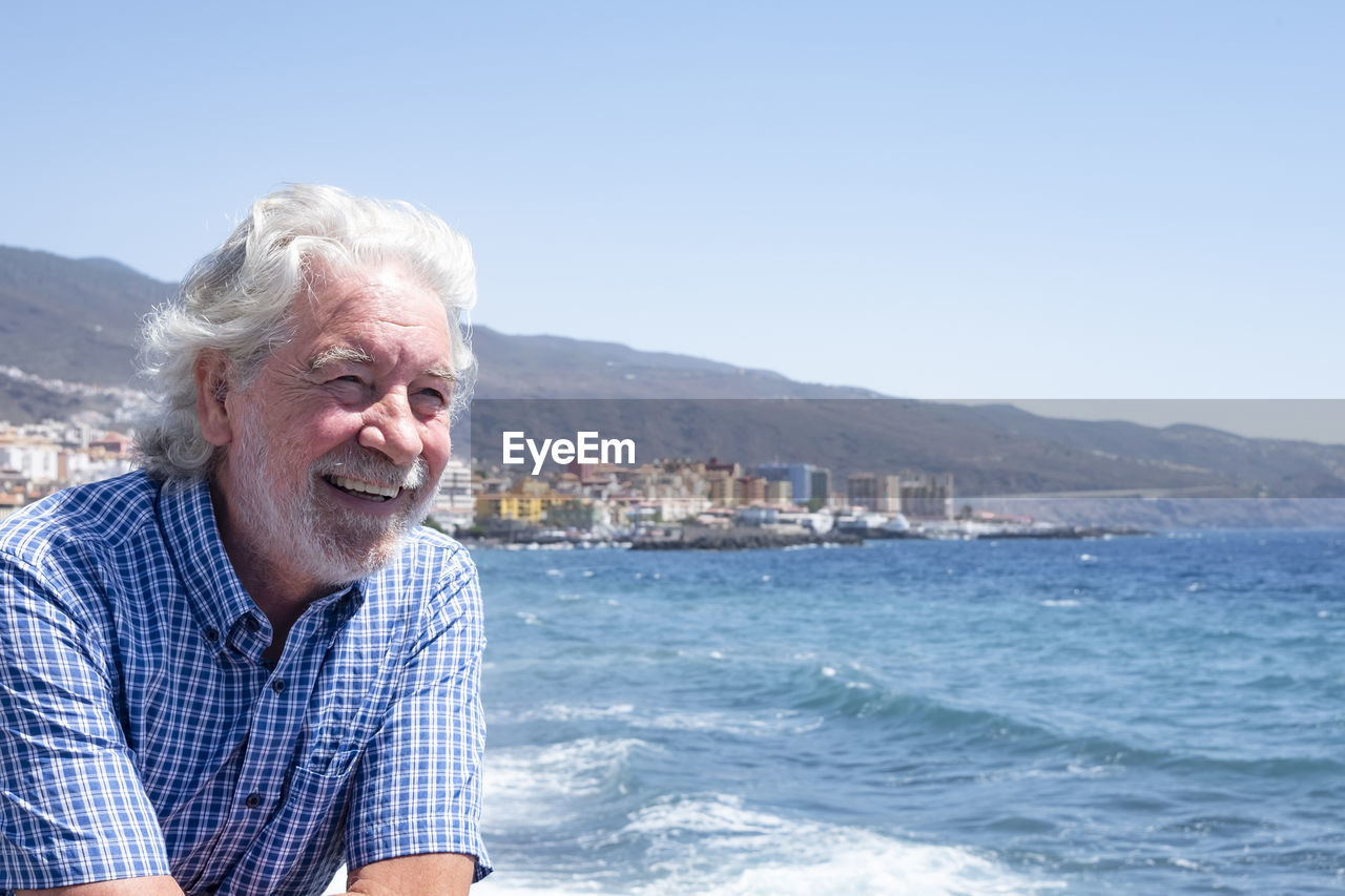 Smiling man in sea against clear sky during day