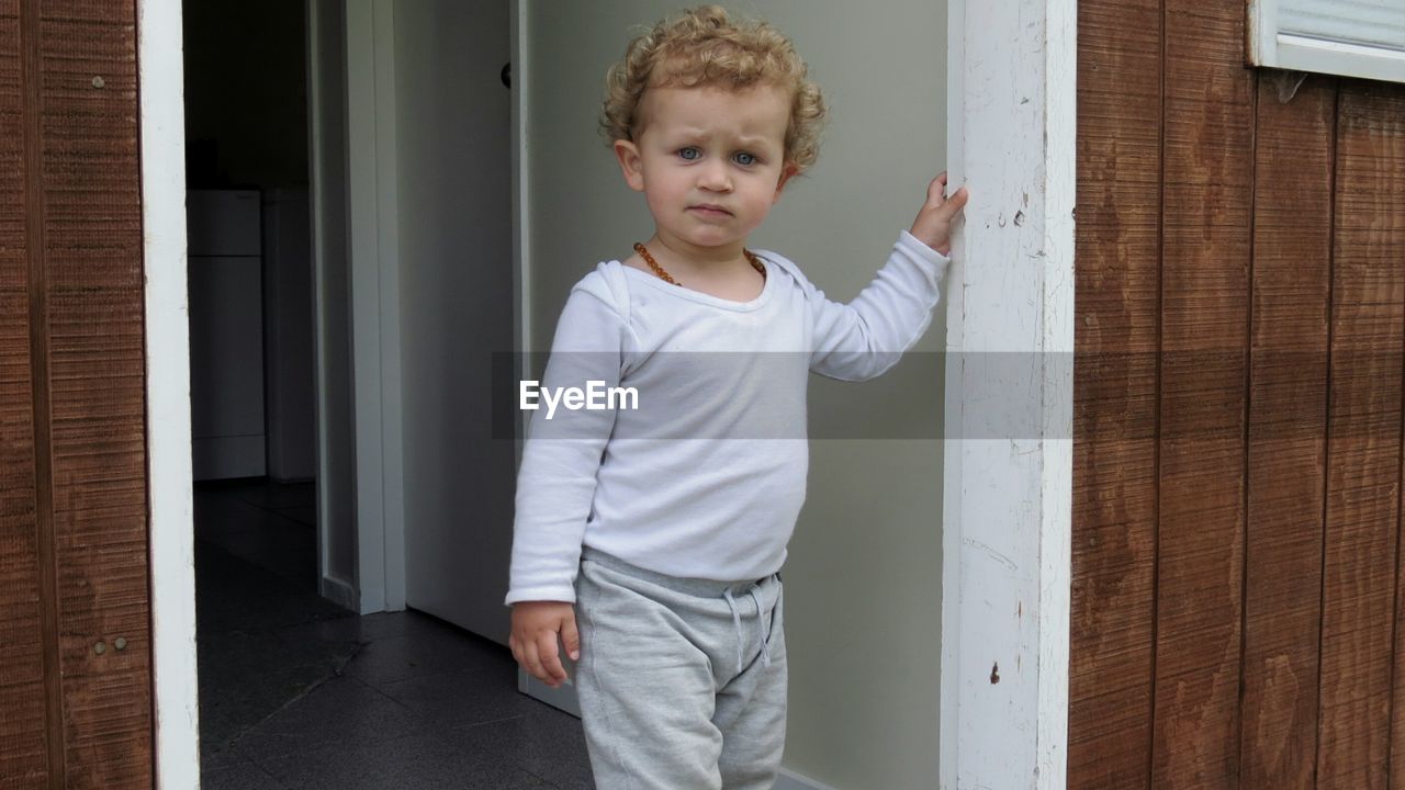 Portrait of boy standing at doorway of house