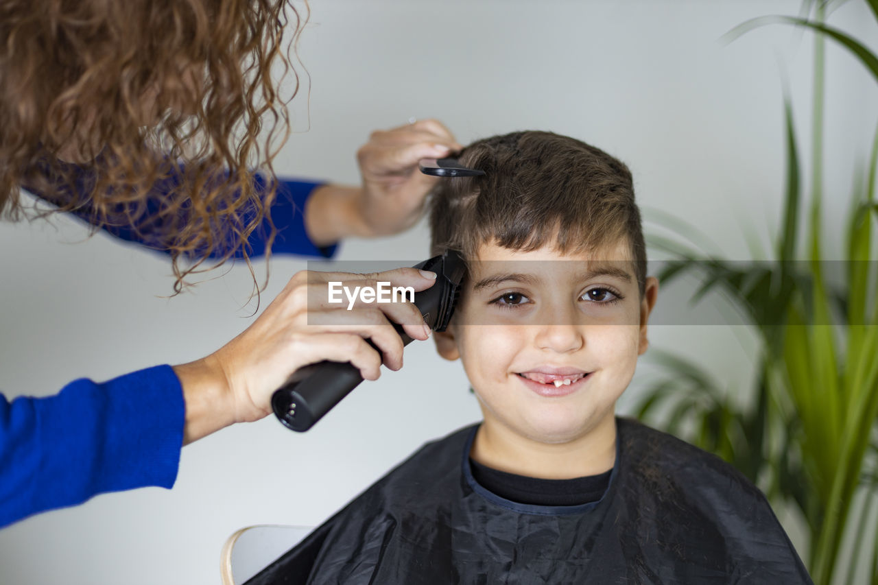 Mother cutting her son's hair at home