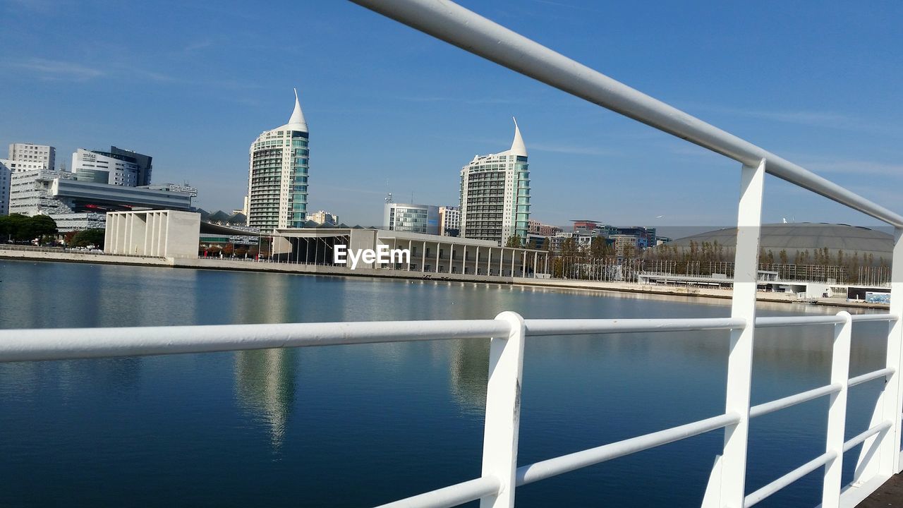 Close-up of railing against river and buildings in city