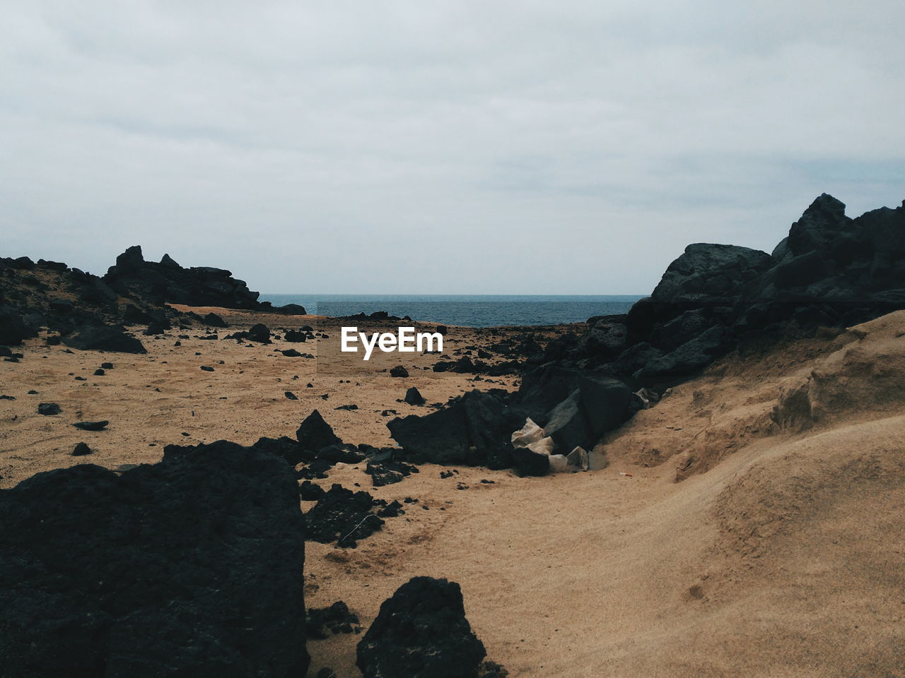 View of rocky beach against cloudy sky