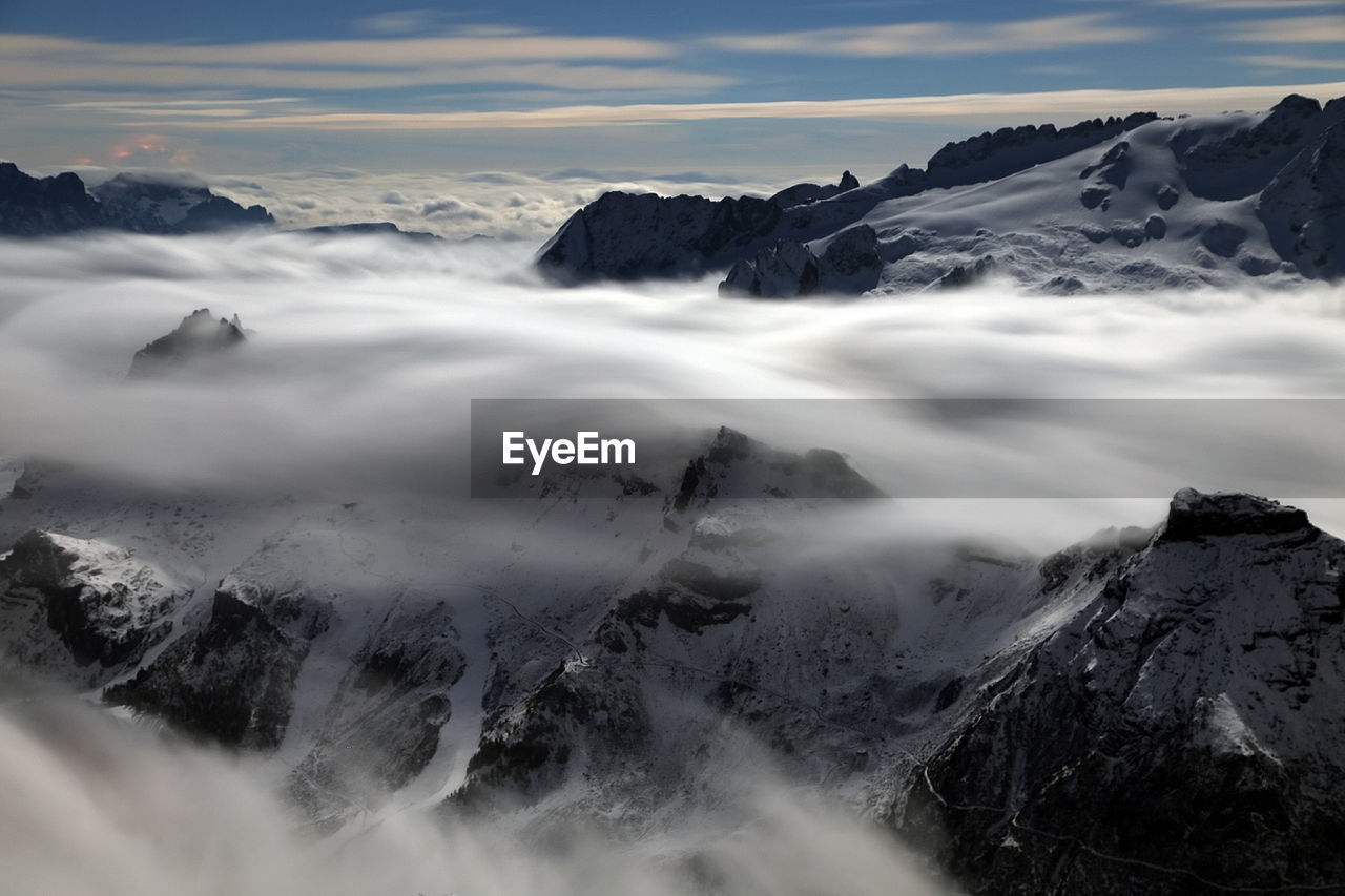 Scenic view of clouds covering snowcapped mountains