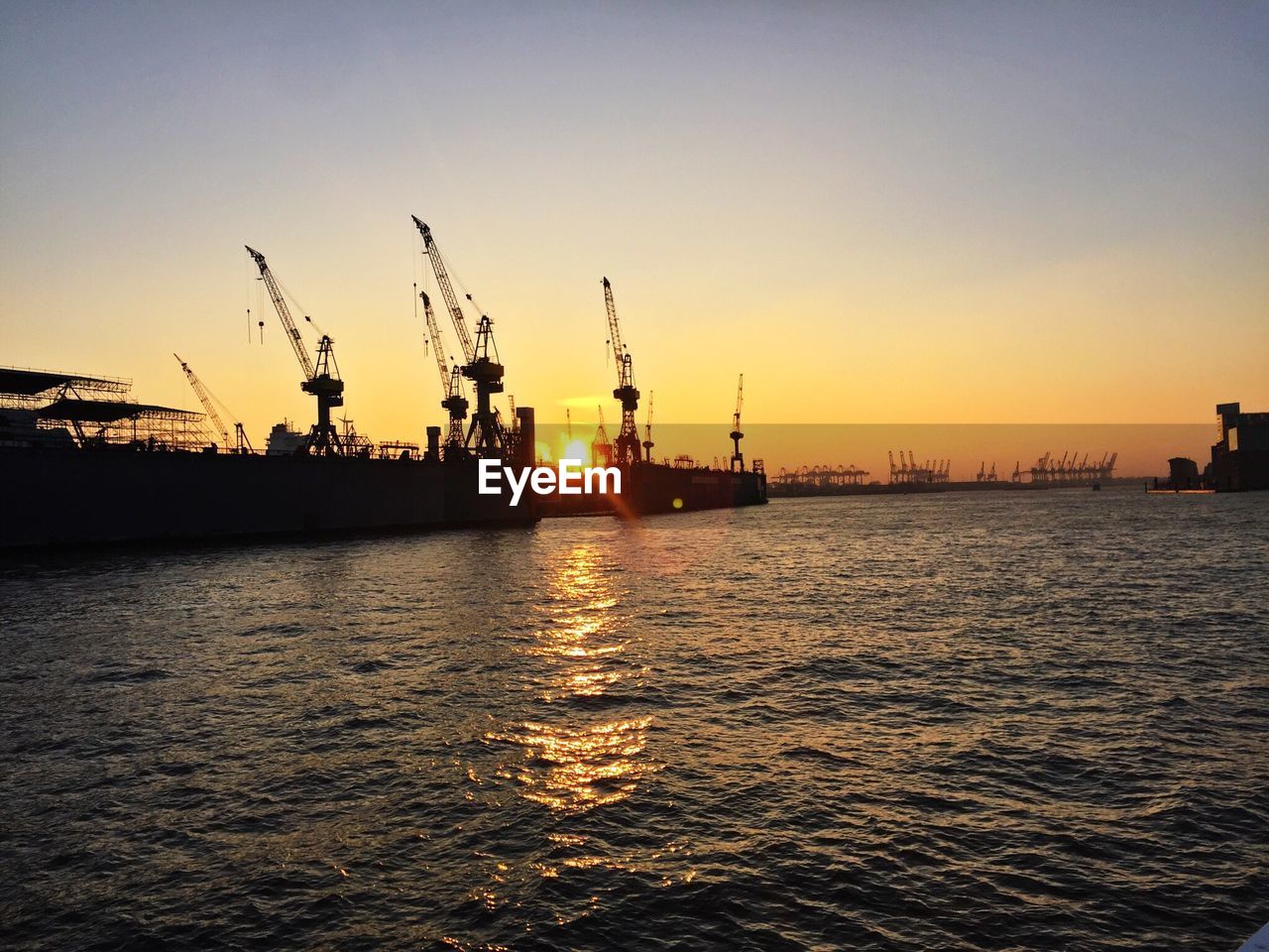 Silhouette commercial dock against clear sky during sunset