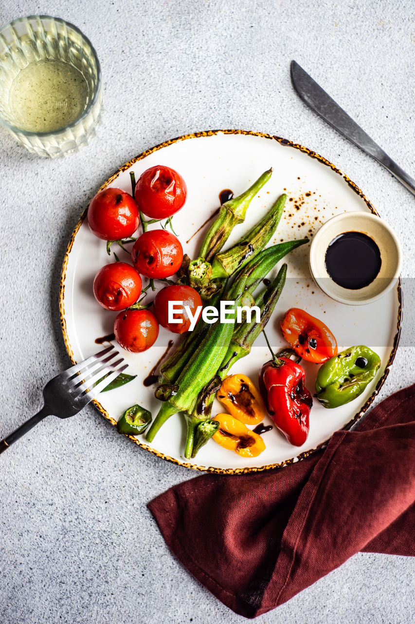 Healthy dinner with bbq bamia, paprika peppers and cherry tomatoes with soy and balzamico sauces served with glass of cold dry wine