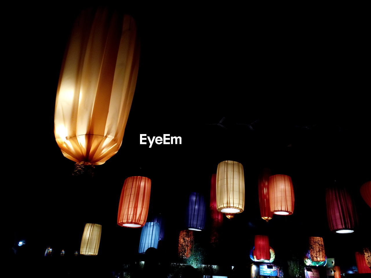 LOW ANGLE VIEW OF ILLUMINATED LANTERNS HANGING AT NIGHT