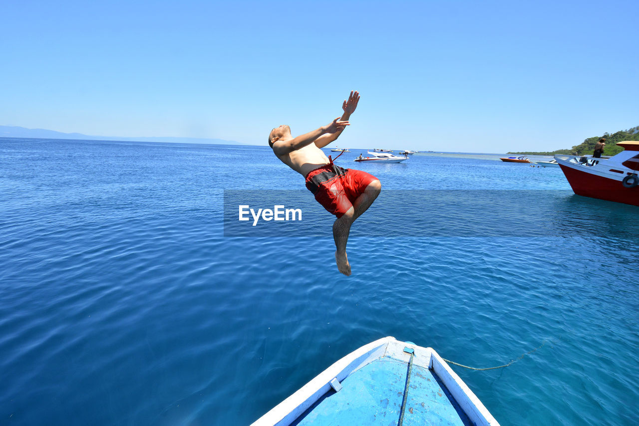 Man backflipping over sea against clear sky