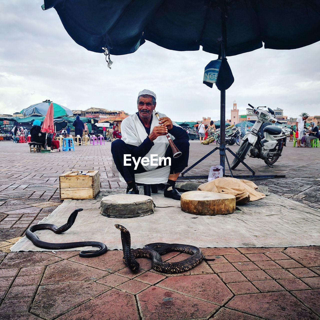 Snake charmer sitting with snakes on footpath