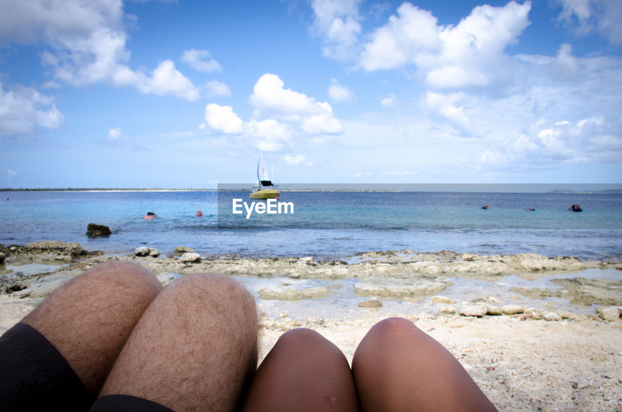 Midsection of couple relaxing at beach