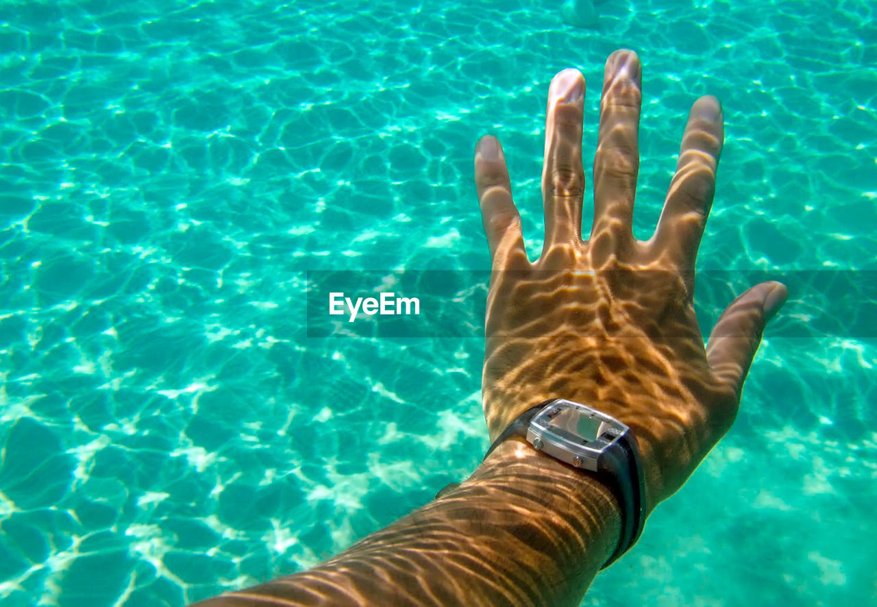 HIGH ANGLE VIEW OF HAND IN SEA