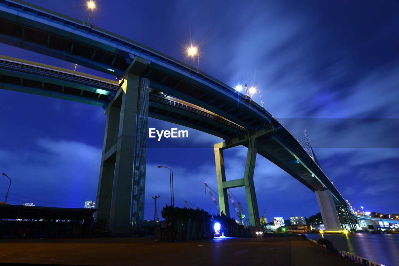 LOW ANGLE VIEW OF ILLUMINATED BRIDGE AT NIGHT