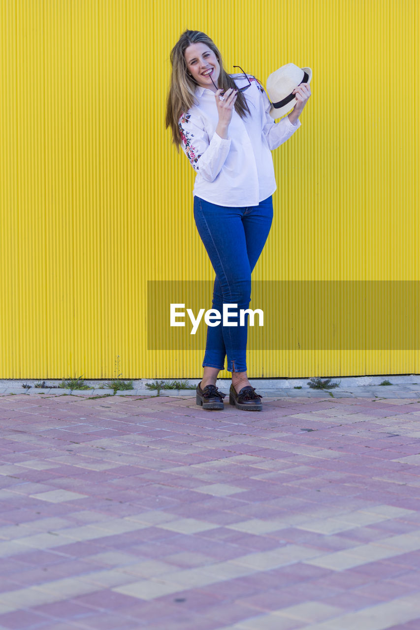 WOMAN STANDING AGAINST YELLOW WALL