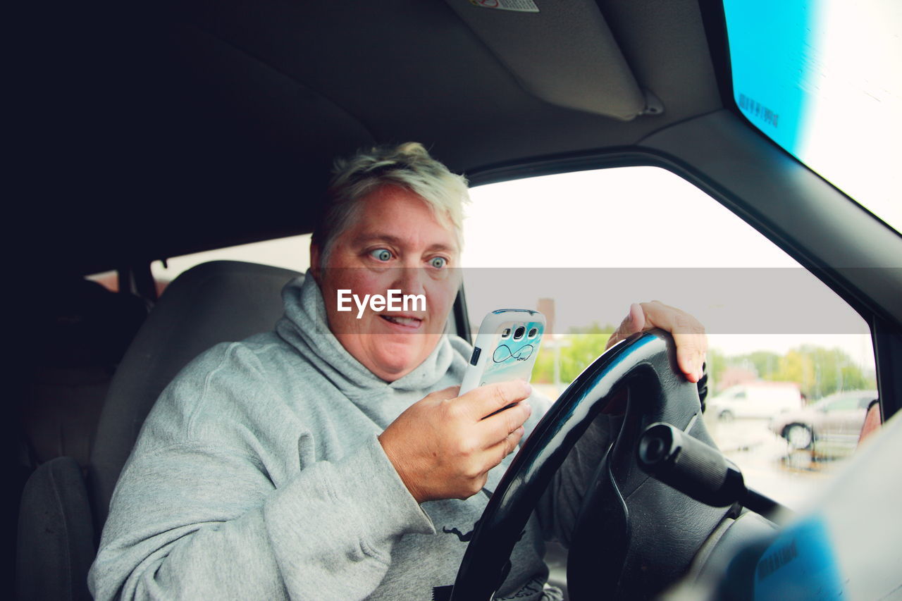 Mature woman using mobile phone while driving car