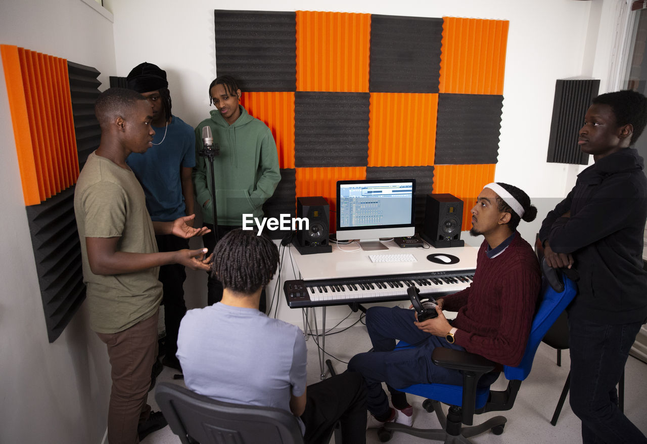 Team of music artists discussing while sitting in recording studio