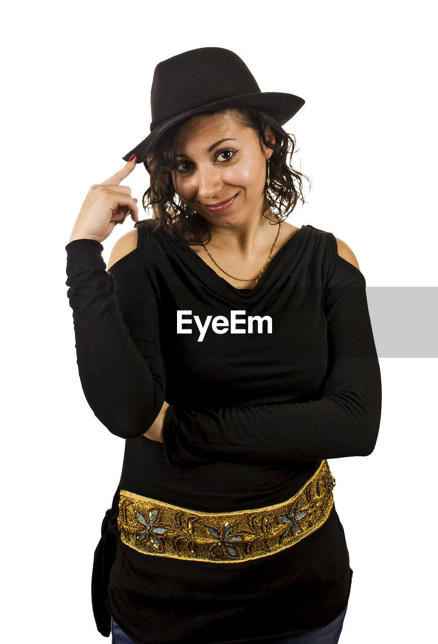 Portrait of smiling woman wearing hat while standing against white background