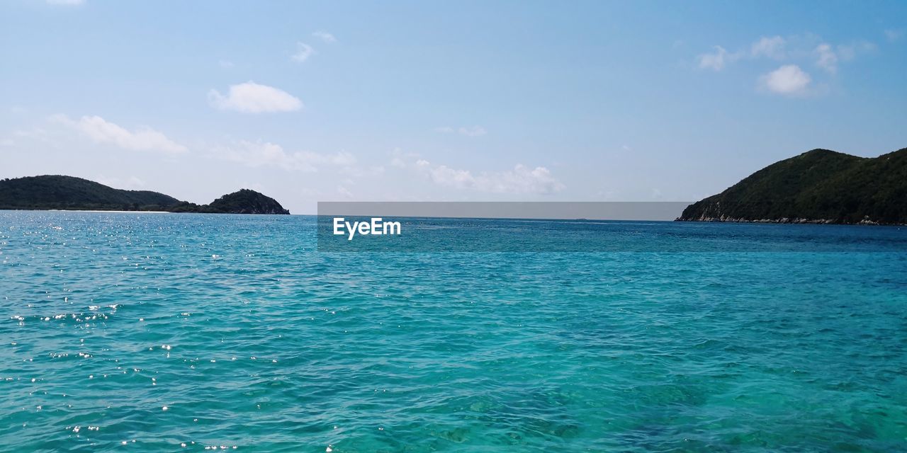 SCENIC VIEW OF SEA AND MOUNTAINS AGAINST BLUE SKY