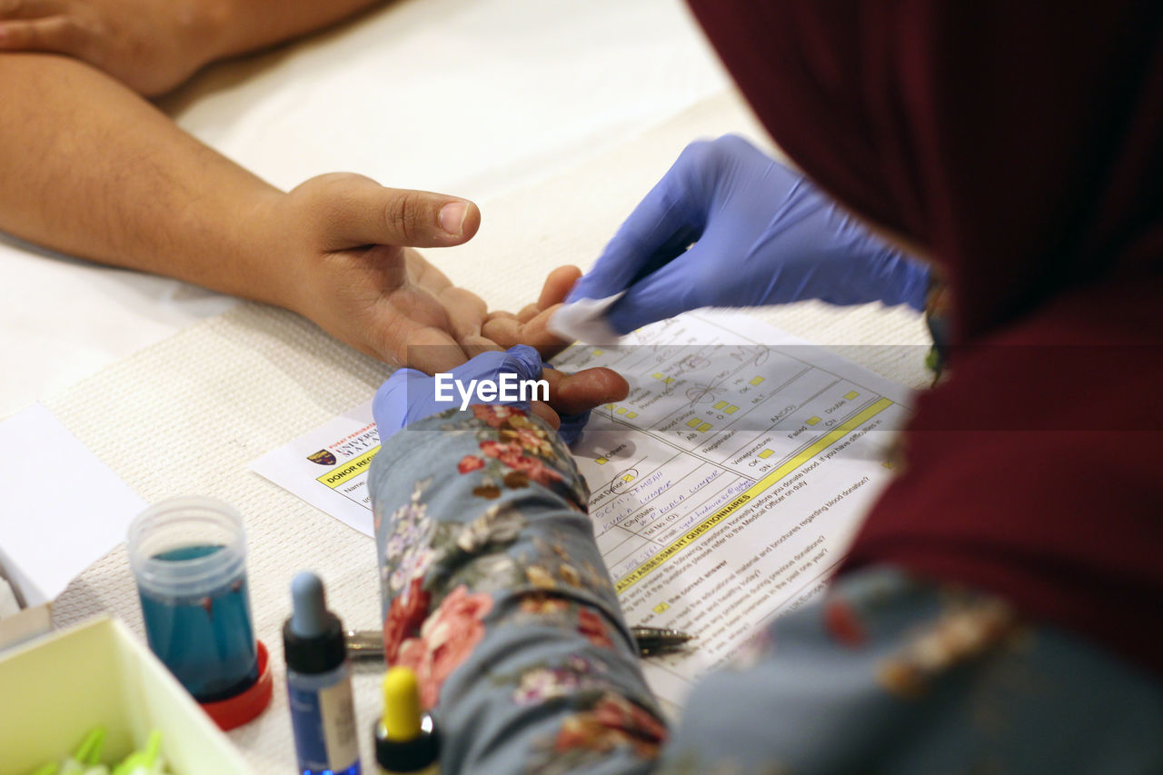 Cropped hands of doctor removing blood sample from patient finger