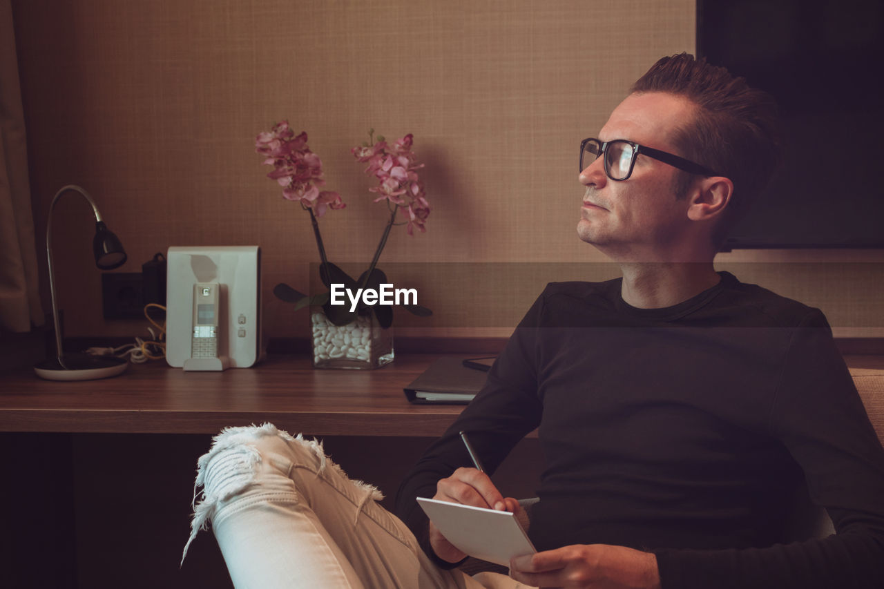 Man looking away while sitting by television set at home