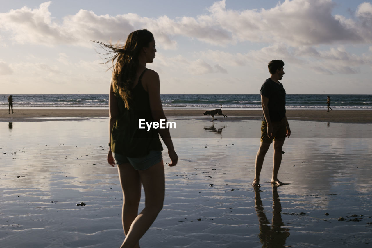 Woman standing on beach against sky