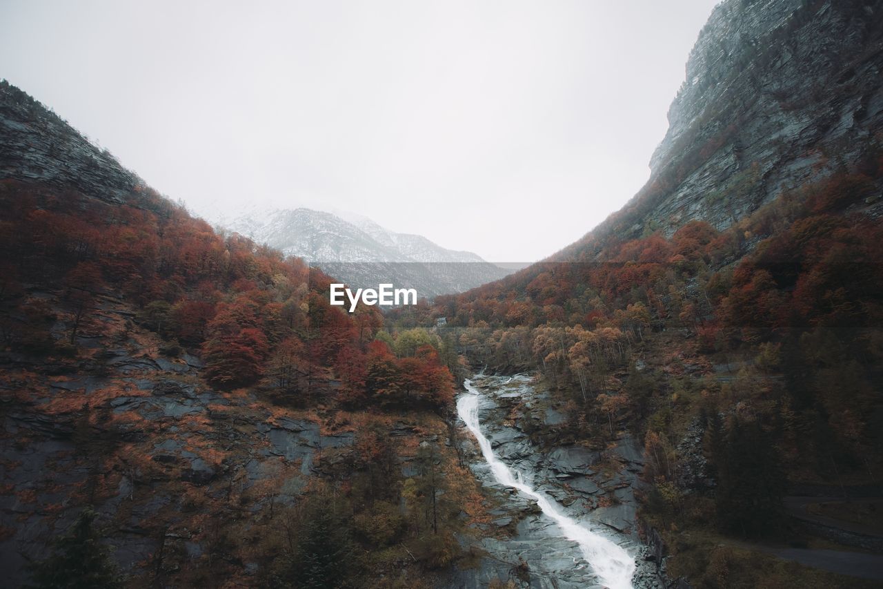 SCENIC VIEW OF WATERFALL AMIDST MOUNTAINS AGAINST SKY