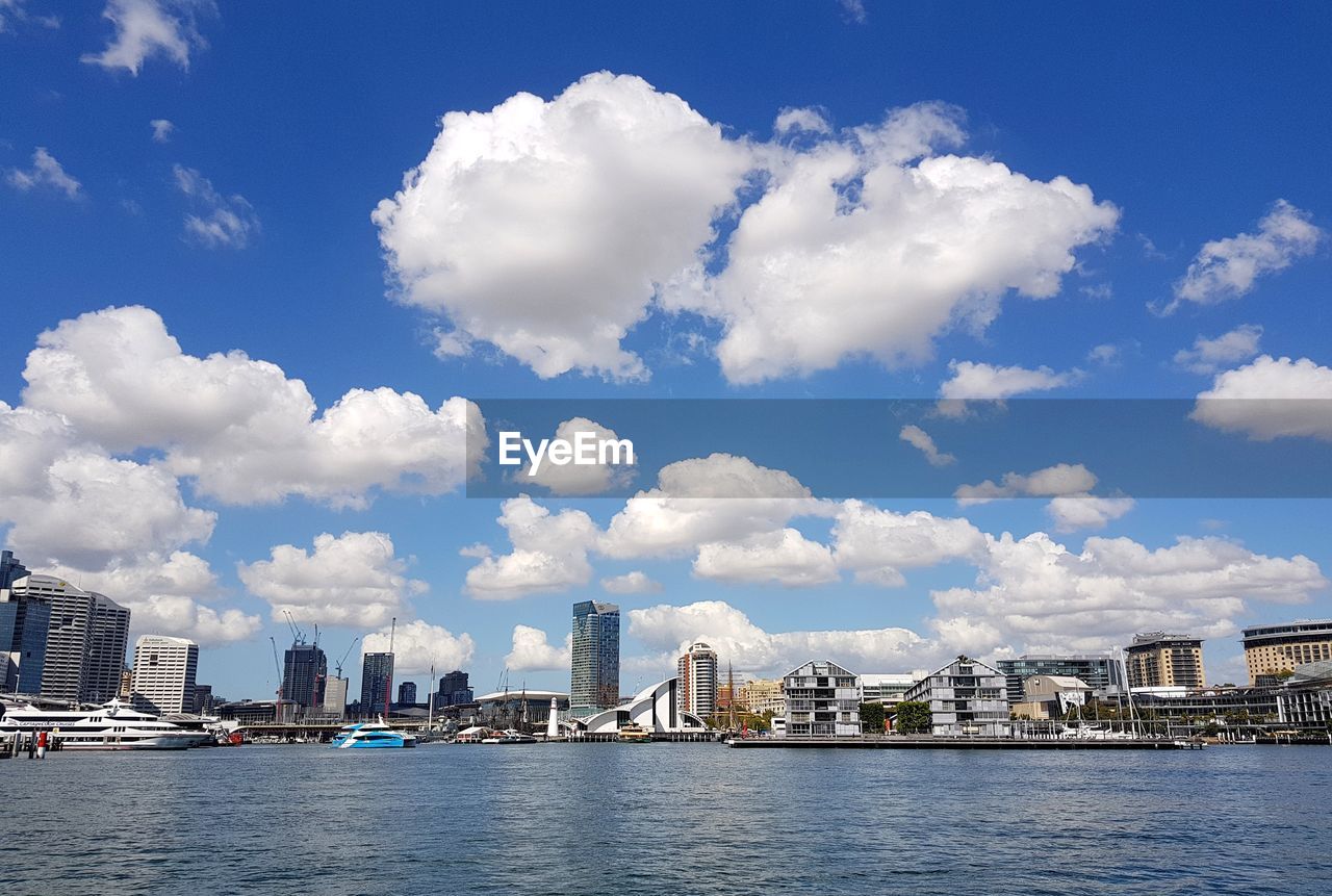 MODERN BUILDINGS BY RIVER AGAINST SKY