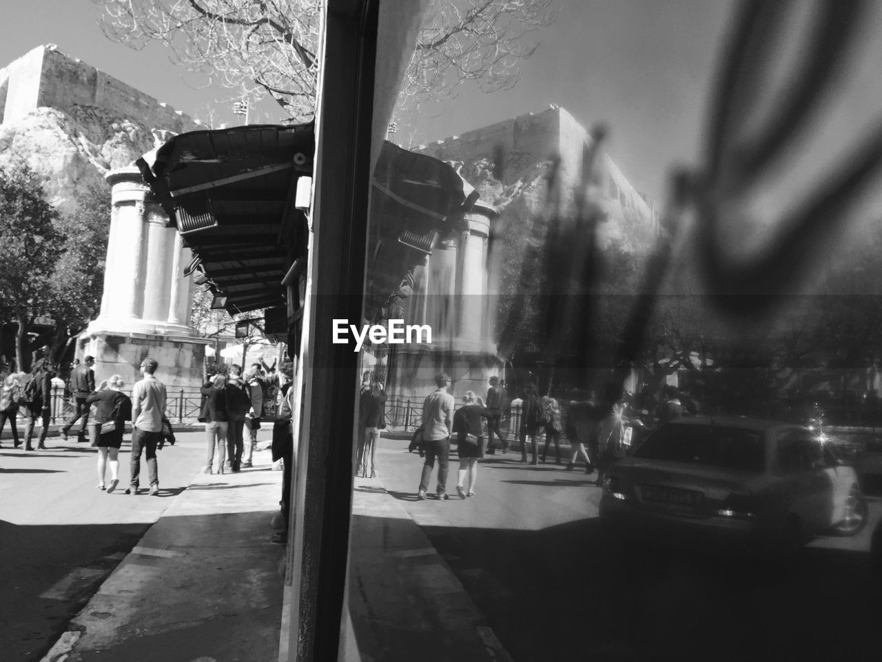 Reflection of people and car on window during sunny day