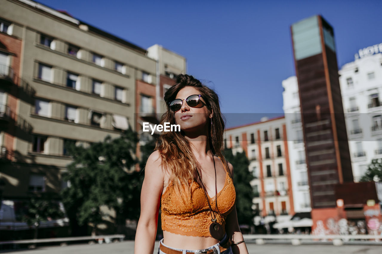 Young woman looking away while standing in city