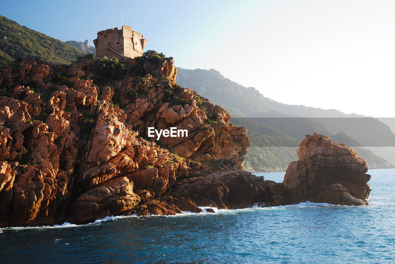 Rock formations by sea against sky