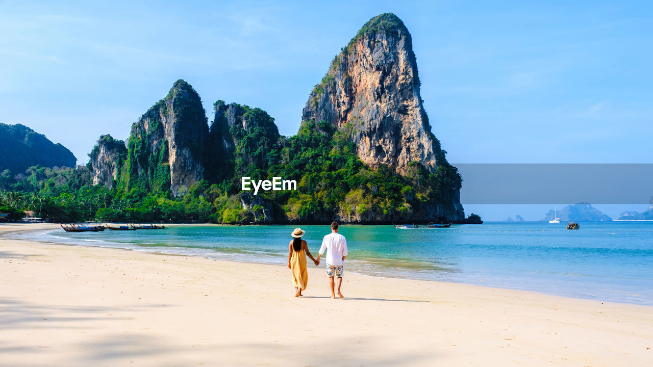 rear view of man standing at beach against sky