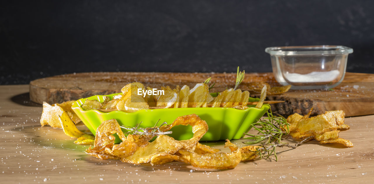 Some deep-fried spiral-sliced potatoes with some thyme on wooden board