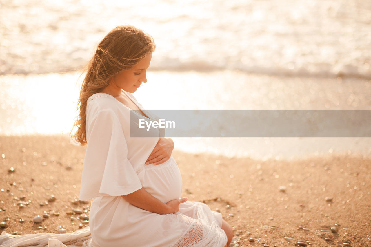 Pregnant woman sitting at beach