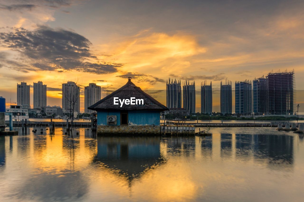 REFLECTION OF BUILDINGS IN SEA AGAINST SKY