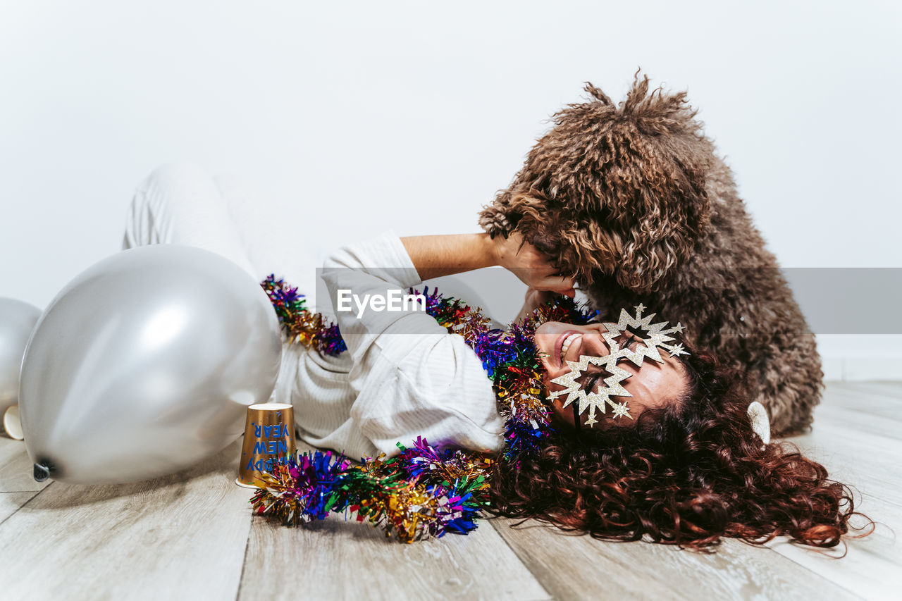 Woman lying on floor with dog against wall at home