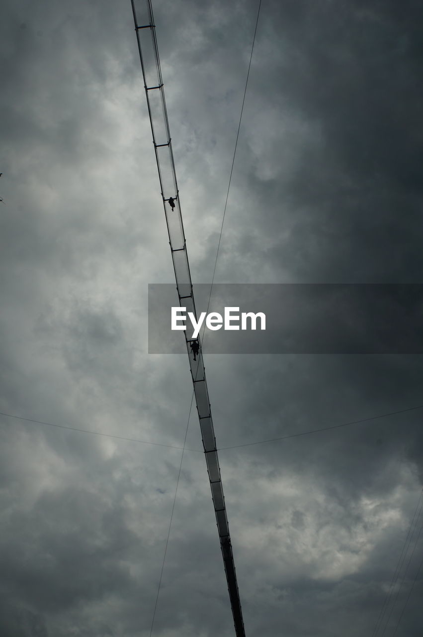 Low angle view of people walking on bridge against sky