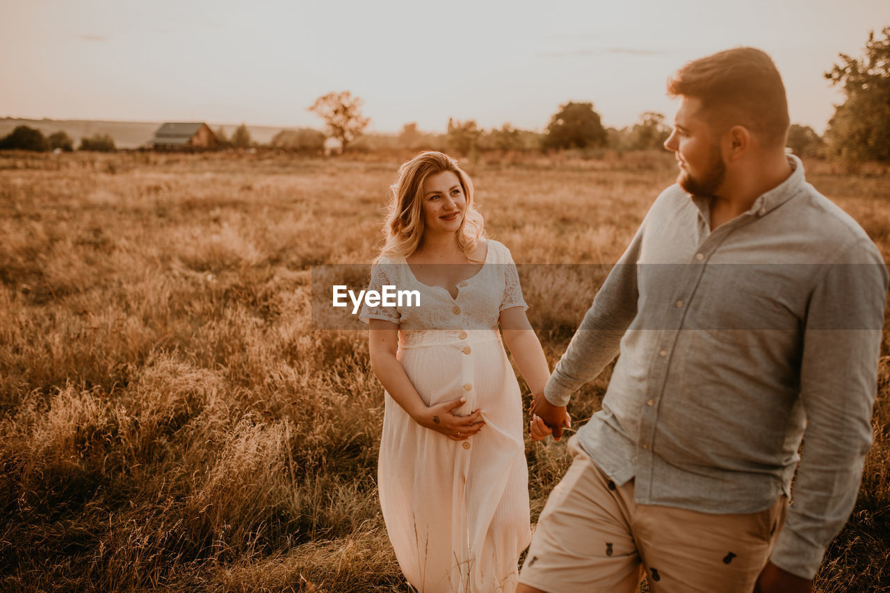 rear view of couple walking on field