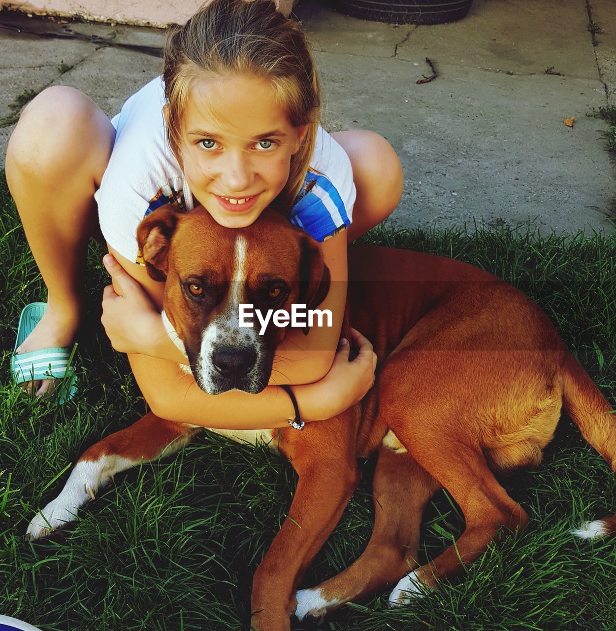 Portrait of girl embracing dog on field