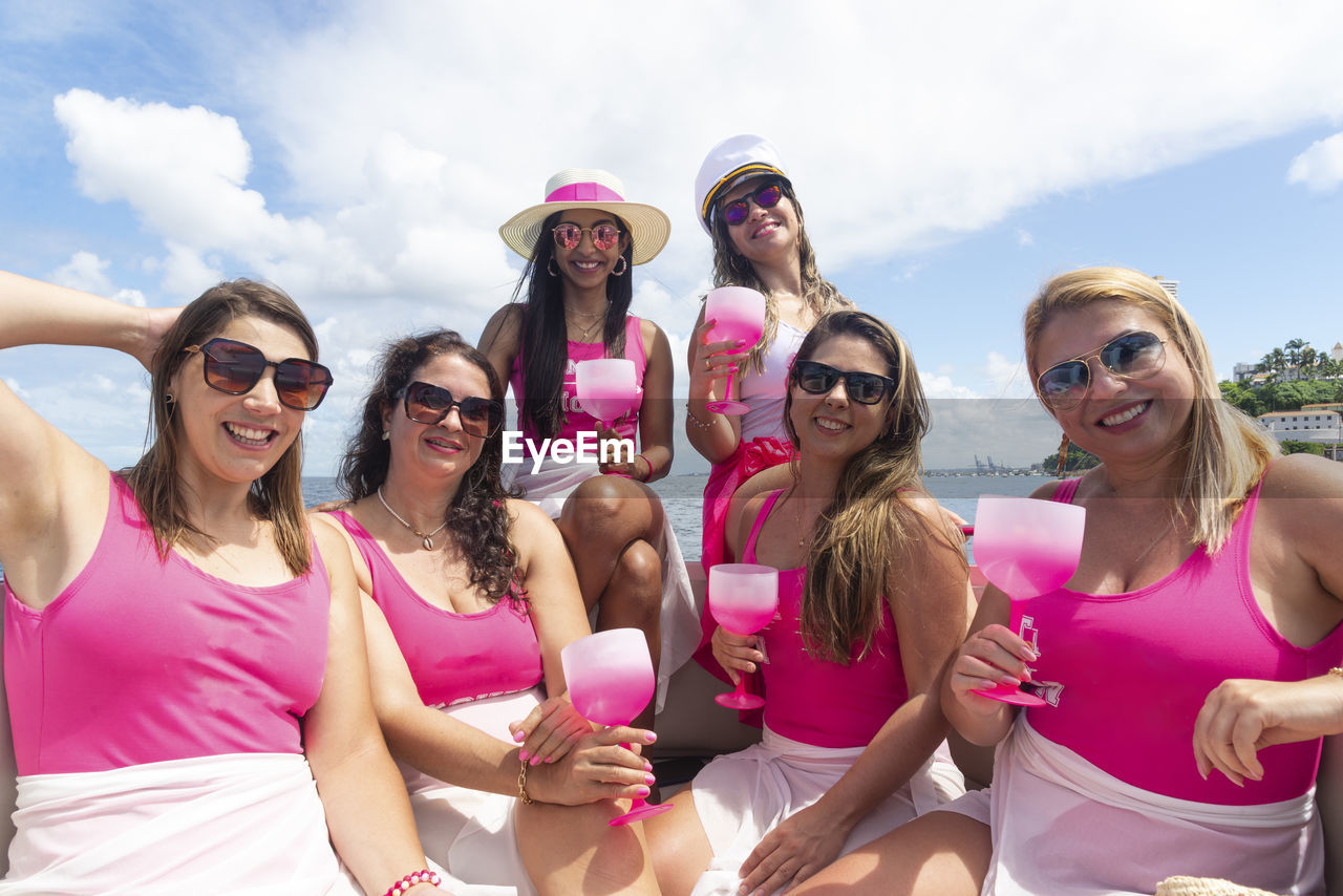 Female friends on top of a boat against the sea in the background.