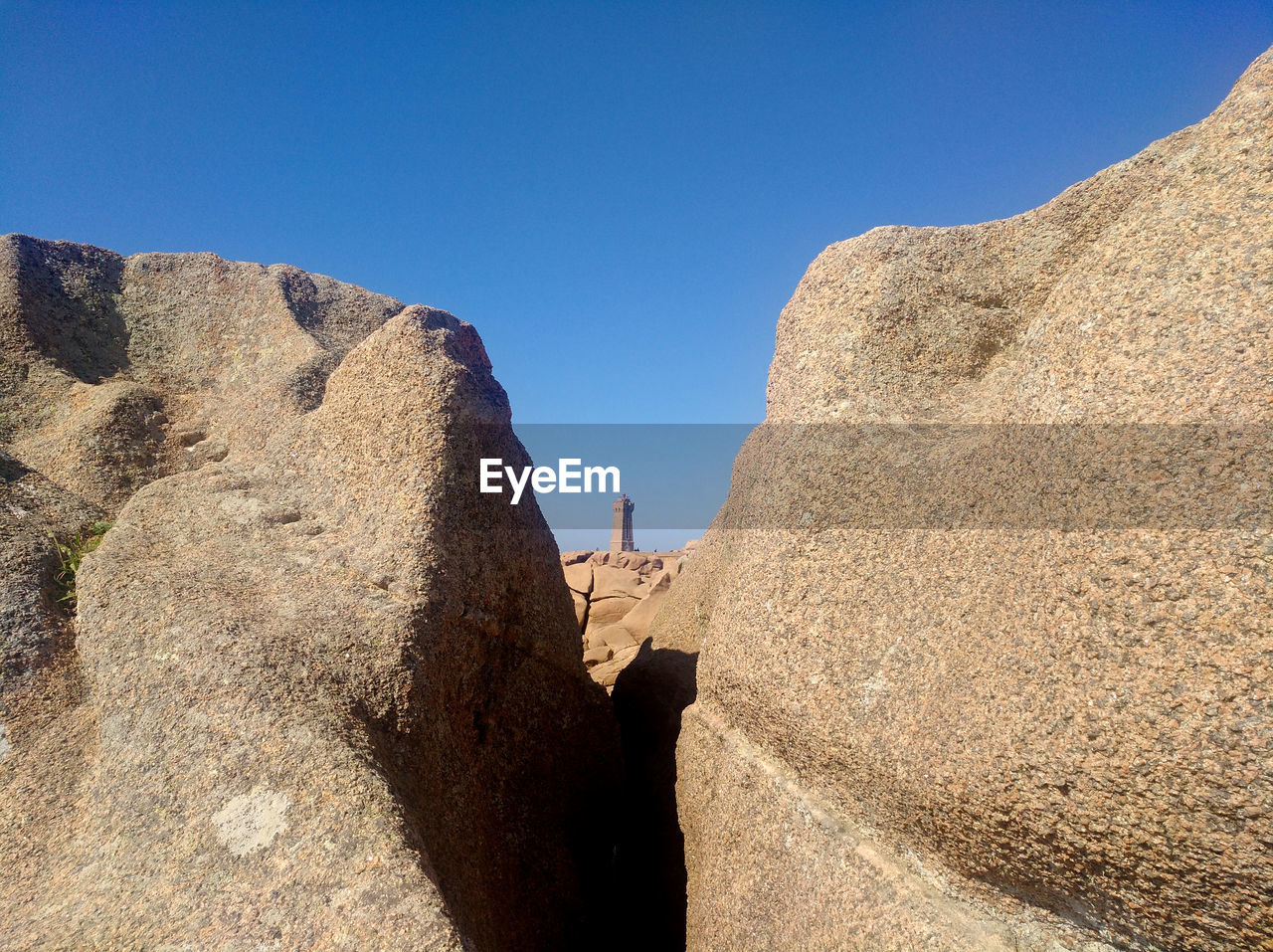 Tower standing on rock against clear blue sky