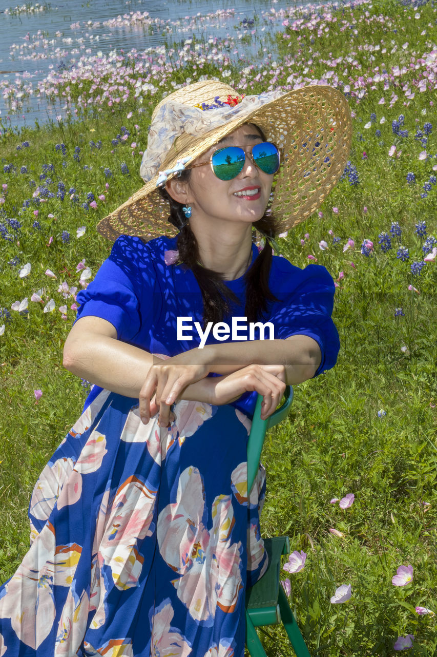 Young woman wearing sunglasses and red flower plants