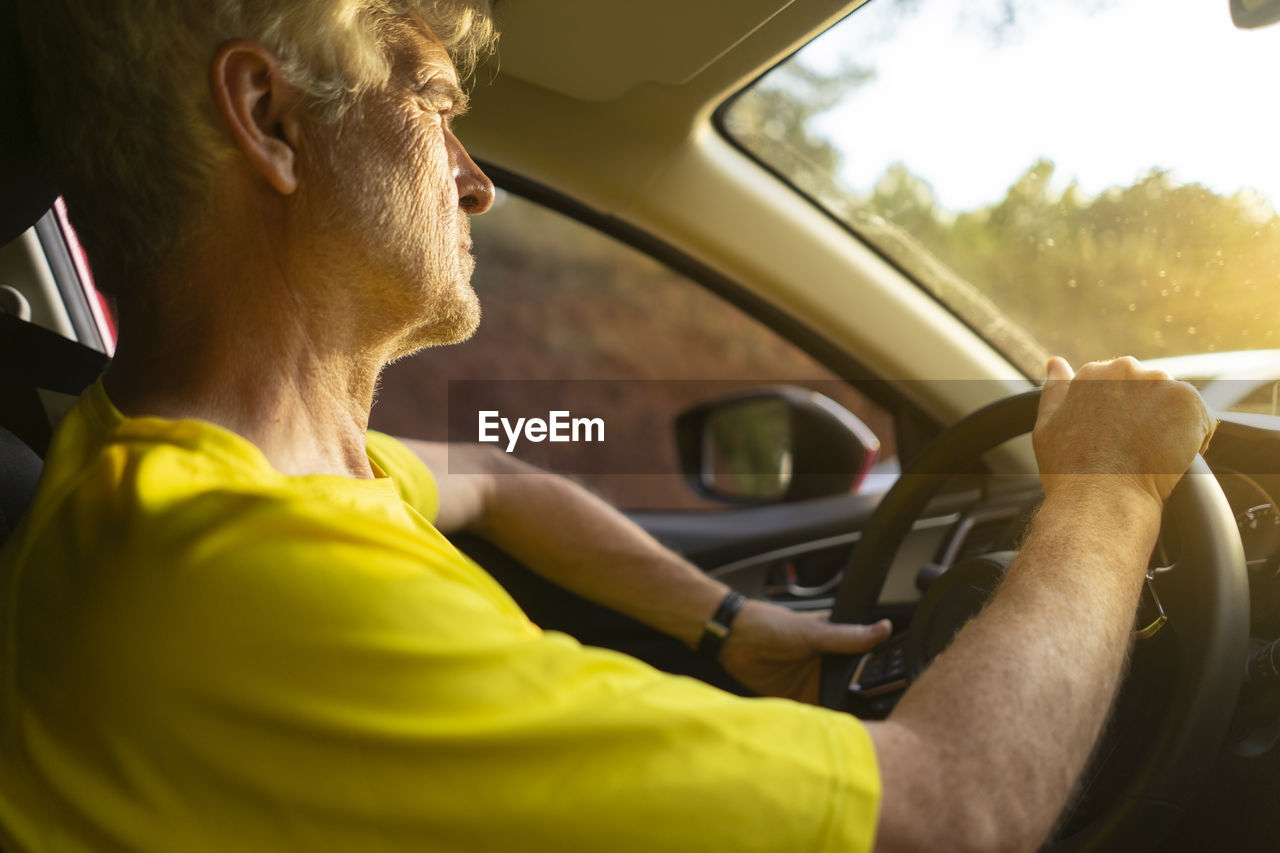 Senior man driving a car during sunset