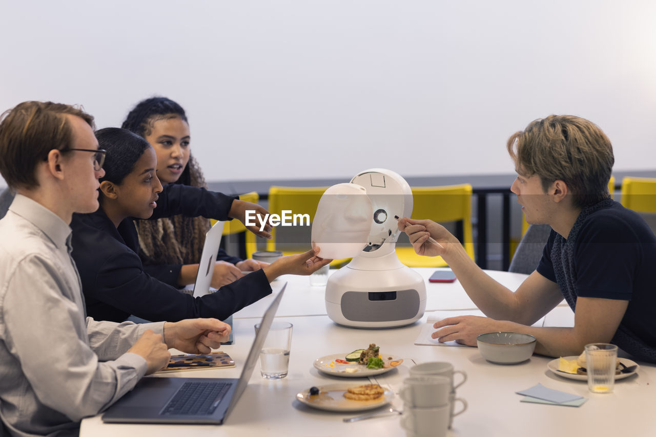 Business people discussing robot voice assistant during meeting