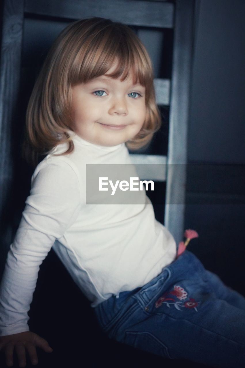 portrait of cute girl sitting on bed