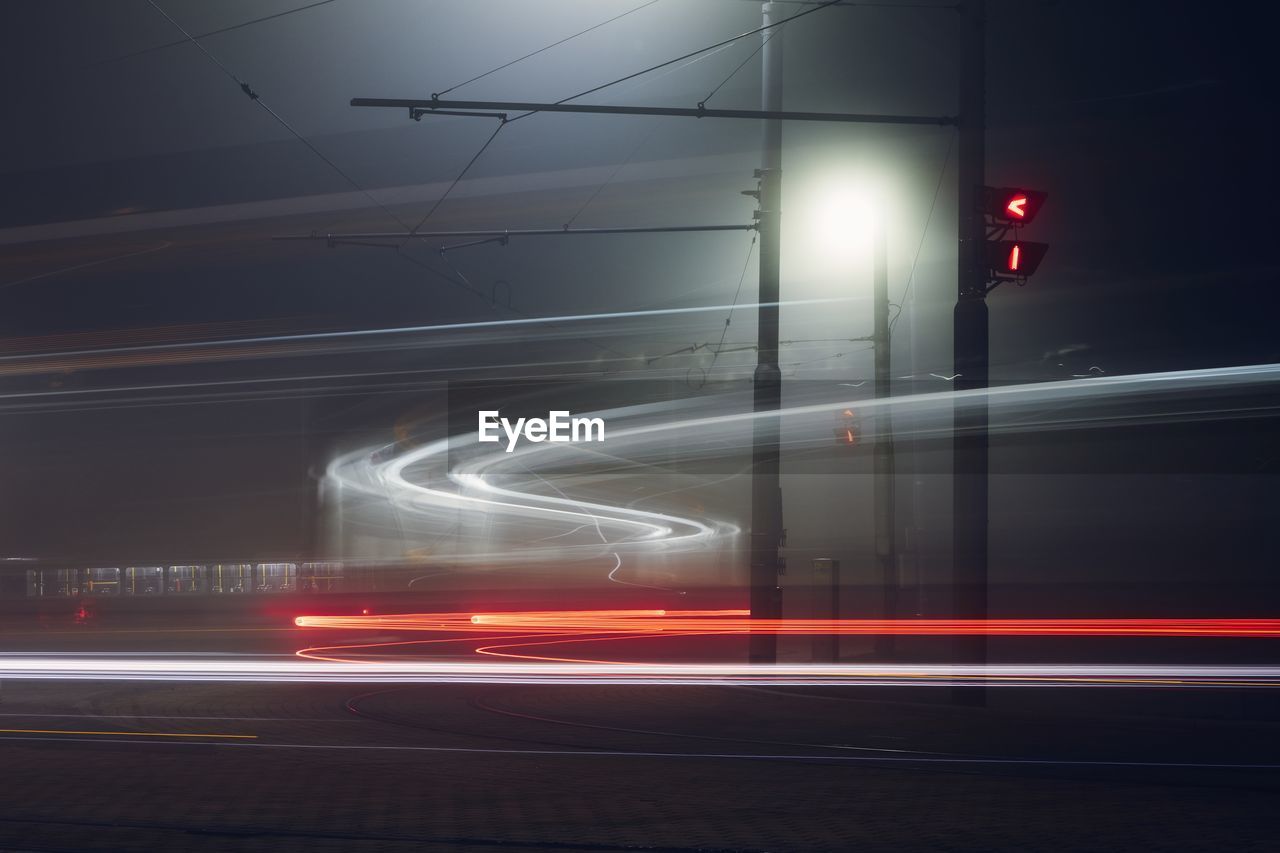 Light trails of trams at station. public transportation during foggy night. prague, czech republic