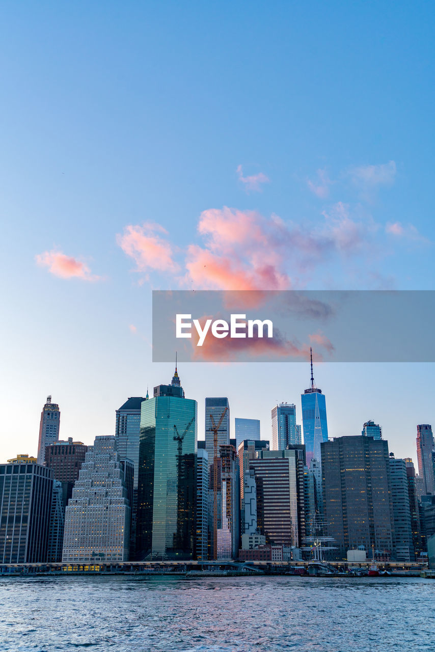 City skyline by river against sky