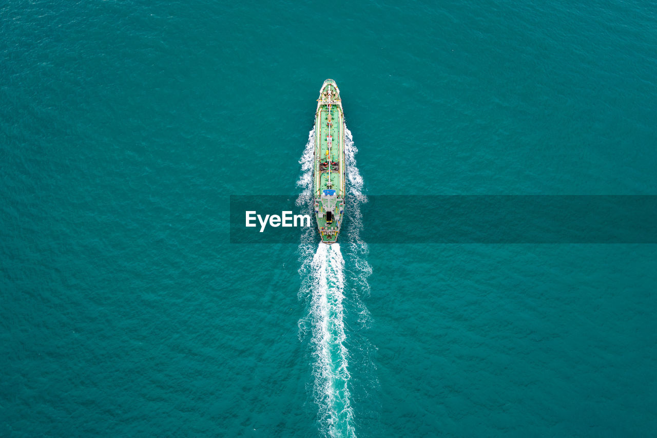 Aerial top view green oil ship tanker full speed with beautiful wave and splash water in line 