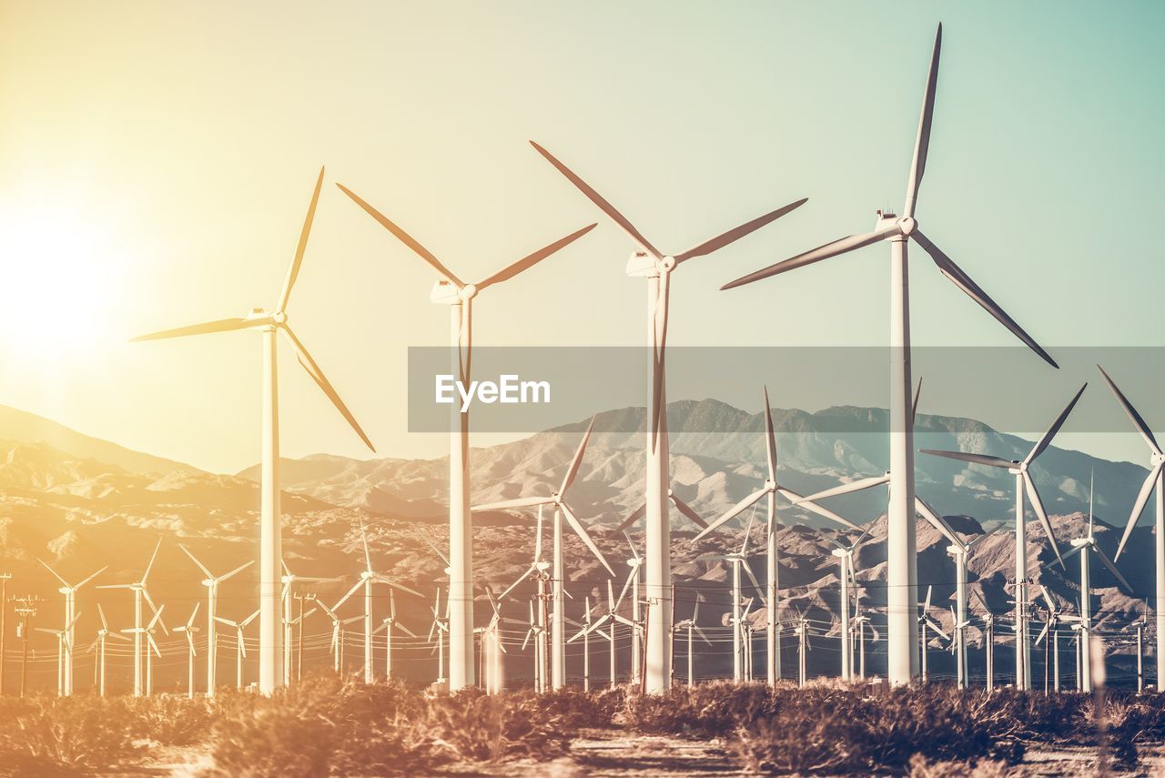 Wind turbines against sky during sunset