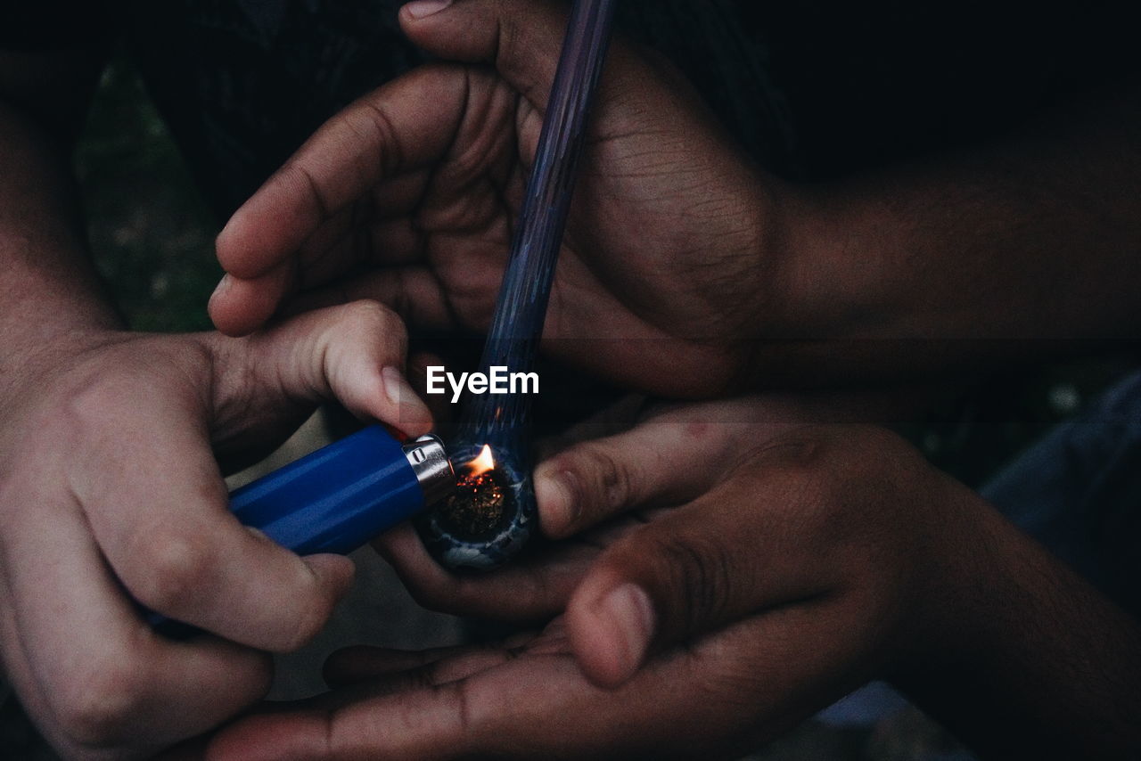 Cropped image of friends lighting smoking pipe