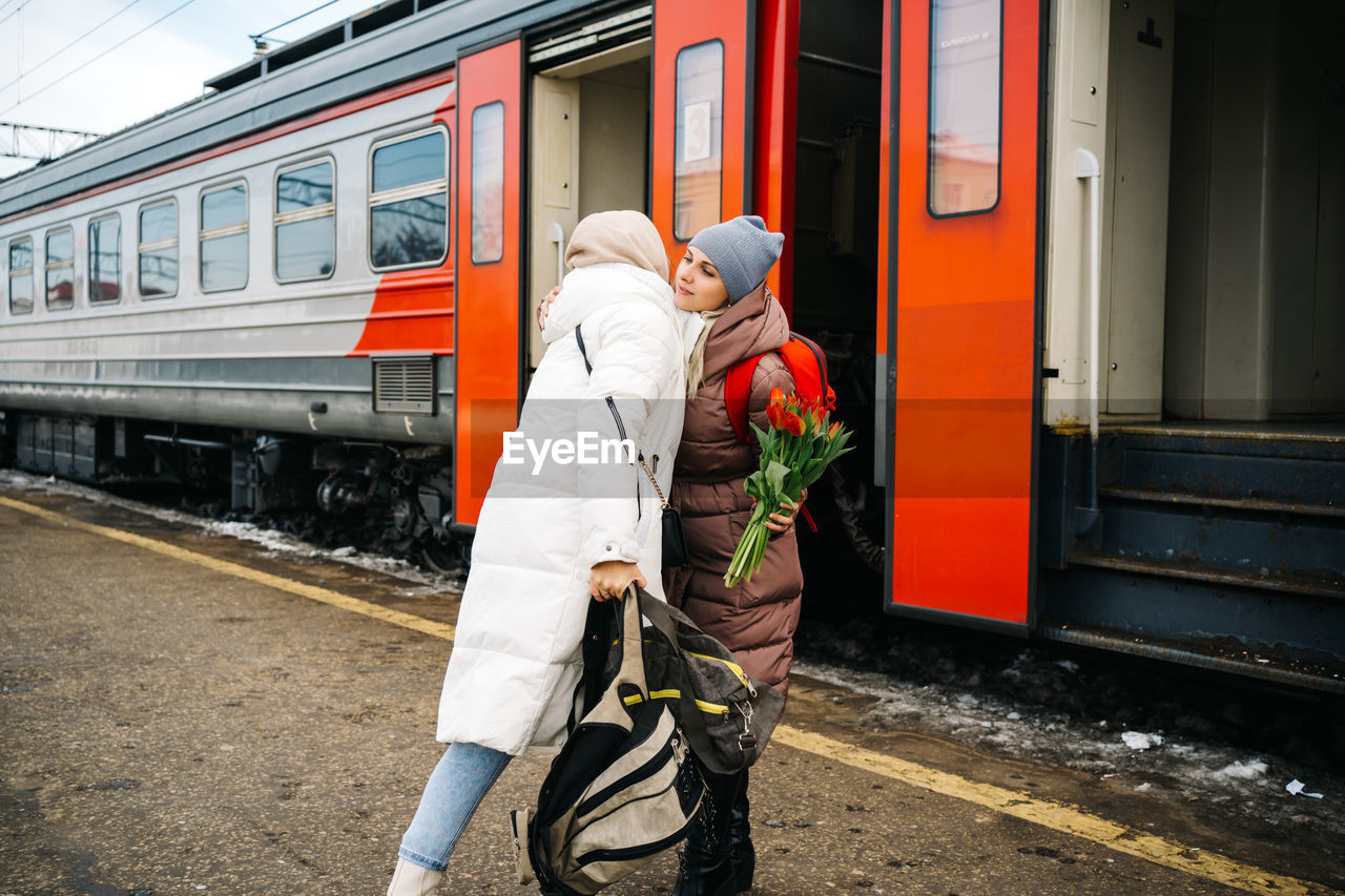 Girls say goodbye hugging on the station platform